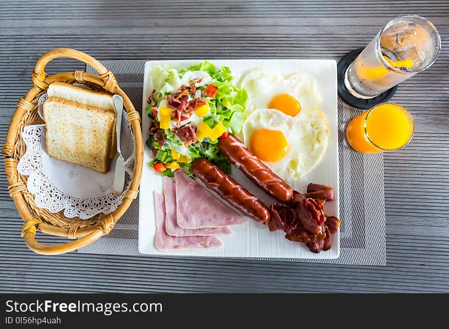 Bread basket, orange juice, fried egg, sausage, ham, salad, fried bacon are foods with health benefits in morning. Bread basket, orange juice, fried egg, sausage, ham, salad, fried bacon are foods with health benefits in morning.