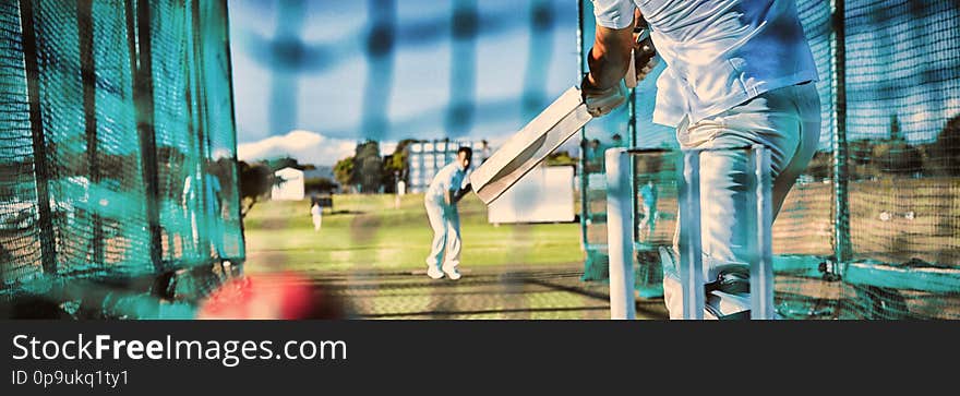 Low section of sportsman playing cricket at field on sunny day