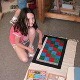 Pinewoods Montessori Schoolcorp Photo - An elementary student doing her math work using Montessori materials. The Montessori math curriculum includes using concrete methods of learning abstract concepts.