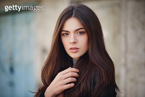 street portrait of a beautiful young brunette girl in a black leather ...