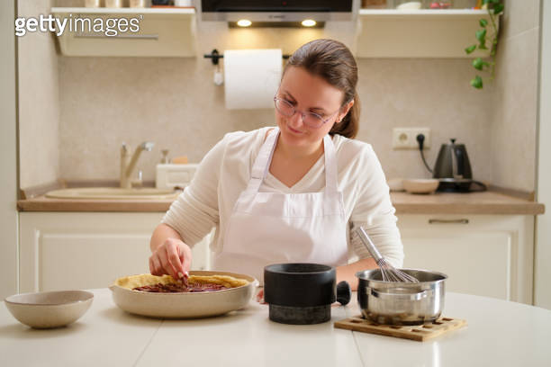 Happy woman making pie in the kitchen at home, healthy food concept ...