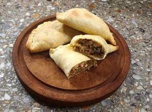 Una foto de Empanadas criollas (morrón, cebolla, huevito duro, pasa de uva y aceitunas), con masa casera🥟