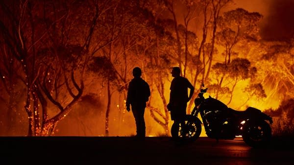 Residents look on as a wildfire burns in Australia