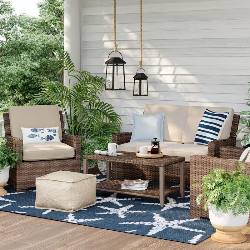 the loveseat in tan on a deck with two matching armchairs and a coffee table