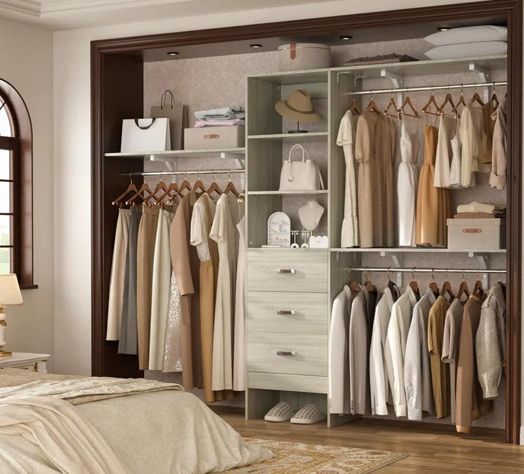 Organized open closet showing clothes, shoes, and accessories neatly arranged on shelves and hangers, next to a bed in a cozy bedroom