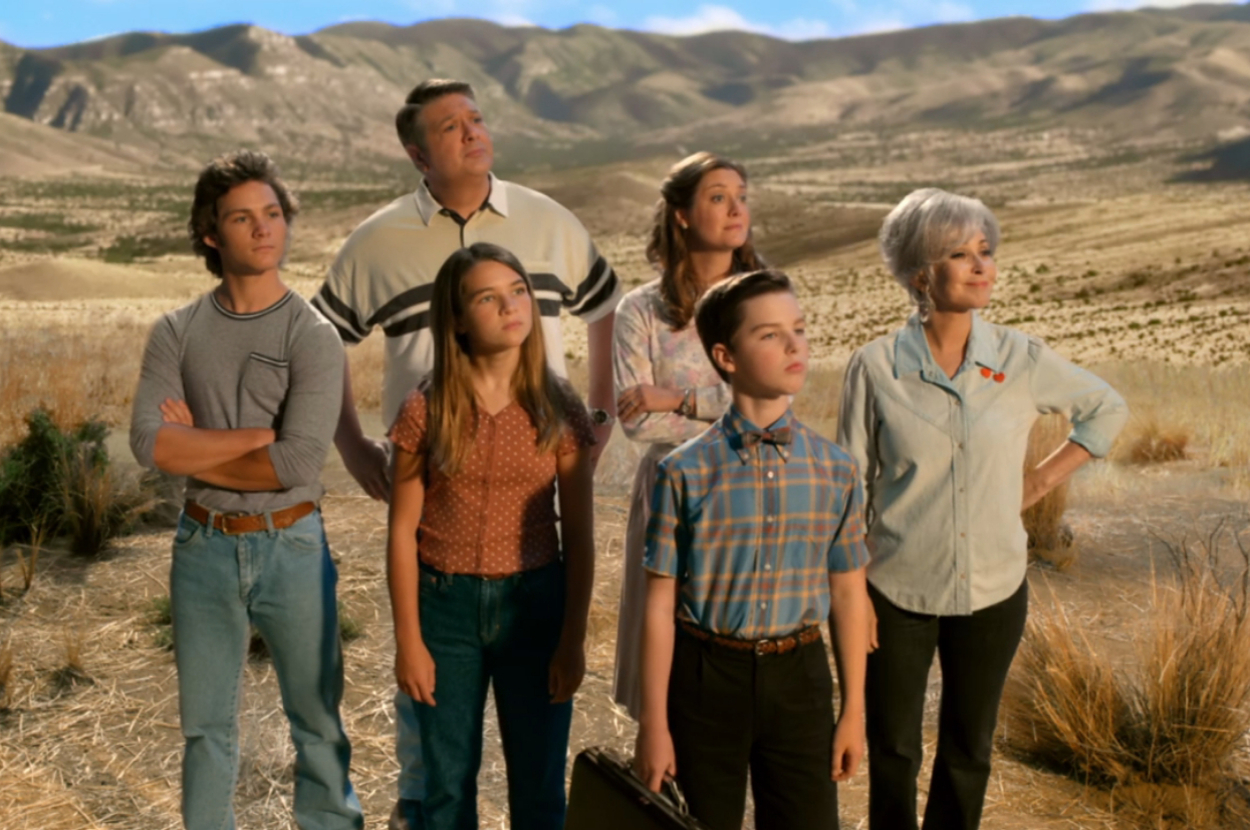 Raegan Revord, Montana Jordan, Lance Barber, Zoe Perry, Iain Armitage, and Annie Potts stand in a rural, desert landscape, looking at something off-screen