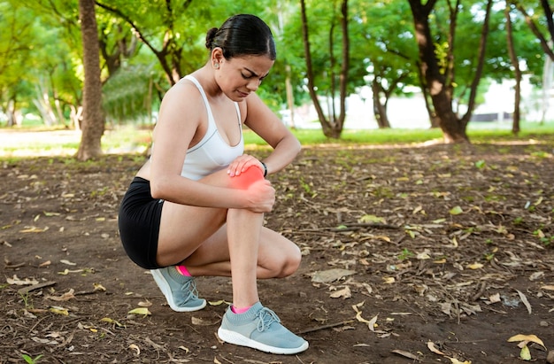 Athlete woman with knee muscle pain athlete girl on the ground\
with knee pain outdoors runner woman with knee pain outdoors\
athlete knee pain and fractures concept