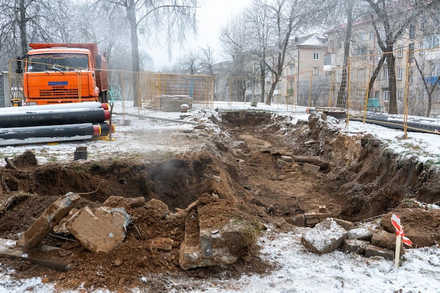 A dump truck with a red cab stands on a construction site in\
winter near new water pipes a road dump truck for transporting\
soil