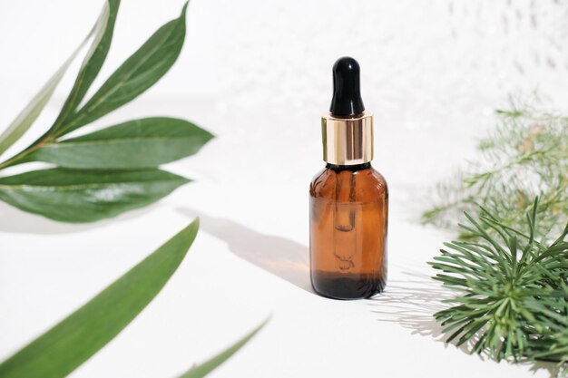 Natural essential oil in an amber glass bottle with dropper\
green leaves background beauty care anti wrinkle serum or oil for\
skin rejuvenation and smoothness