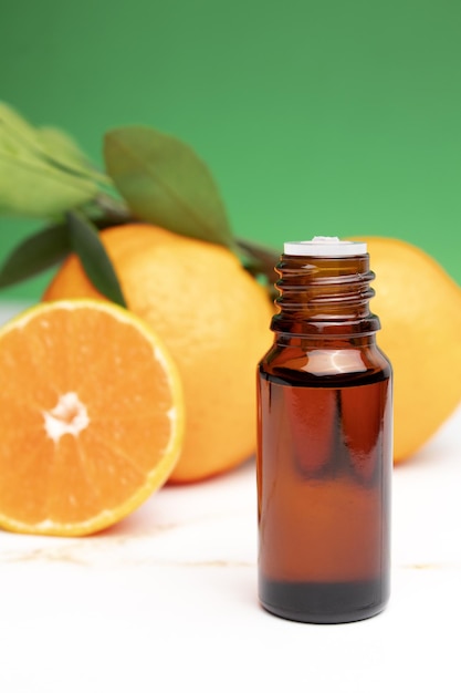 Natural organic orange essential oil for skin face and body\
health care moisturizing aromatherapy detox treatment antistress\
effect fresh fruit green leaves green background