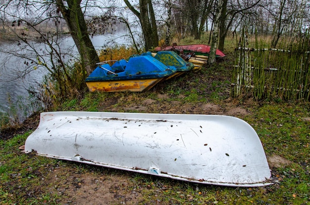 Old boats and catamarans are rusting in the open dump in the\
forest at the foot of the river bank of outdated water equipment\
nearby grow large birches and other trees