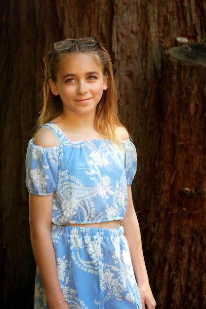 Premium Photo | Smiling girl standing against tree trunk