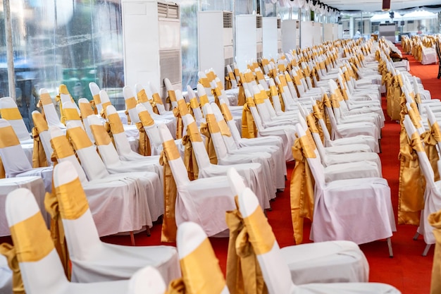 Temporary air conditioner indoor tent for outdoor event in the\
day inside tents has red carpet and a lot of chair covered by white\
cloth and golde ribbon on it