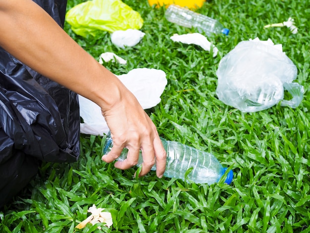 Volunteer spirit with conserving and preserving environment by\
garbage collection plastic water bottle with black bag dumped in\
yellow trash to recycle.