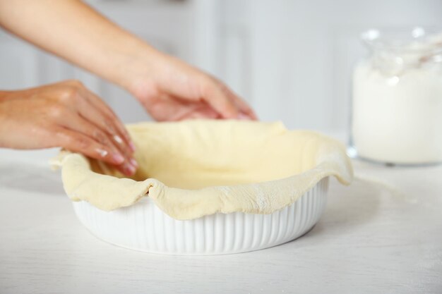 Premium Photo | Woman making pie on wooden table on light background