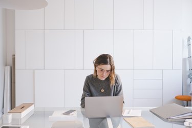 Young female entrepreneur using laptop at desk in workshop