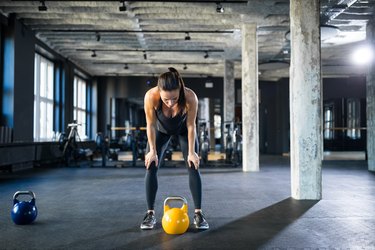 Tired athlete standing with hands on knees in gym