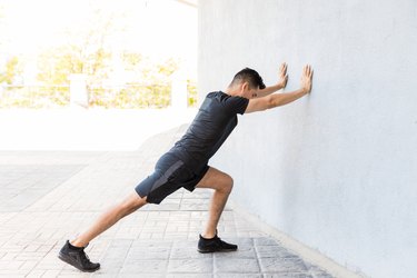 a man bouncing while doing a standing calf stretch outside, as an example of what can cause plantar fasciitis flareups