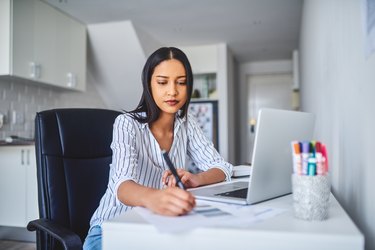 a person sitting in a home office chair while working in their kitchen