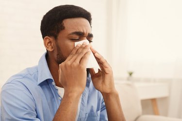 man at home blowing his nose to try to get rid of hard boogers