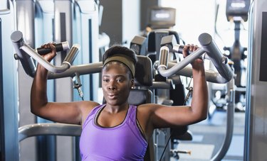 Person wearing purple tank top working out at the gym to burn fat