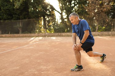 an older adult wearing black shorts and a blue t-shirt does a lunge exercise to prevent tingling in legs after exercise