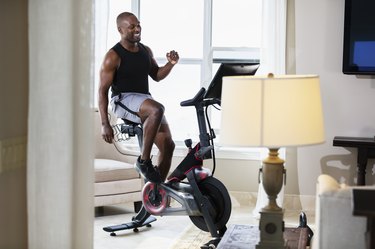 black man enjoying the benefits of stationary bike workouts at home in her living room