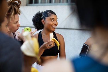 Woman eating banana after working out wondering how much potassium do I need to stop leg cramps