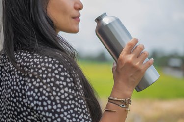 Asian Woman Drinking Water from Reusable Metallic Water Bottle