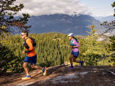 Man and woman trail running and wearing gps watches