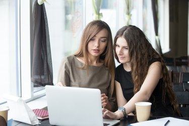 Two young beautiful women chatting in cafe