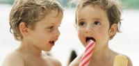 Two small children sharing popsicles, head and shoulders, portrait.