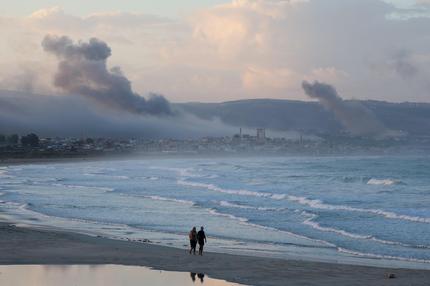 Krieg in Israel und Gaza: Menschen gehen an einem Strand spazieren, während 23. September 2024 nach israelischen Angriffen Rauch über dem Südlibanon aufsteigt.