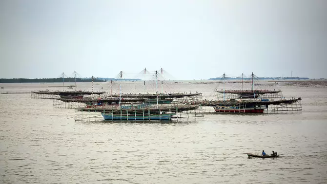 Nelayan menggunakan perahu melintas di dekat karamba jaring apung kerang hijau di laut Dadap, Tangerang, Banten, Selasa, 7 Februari 2023.