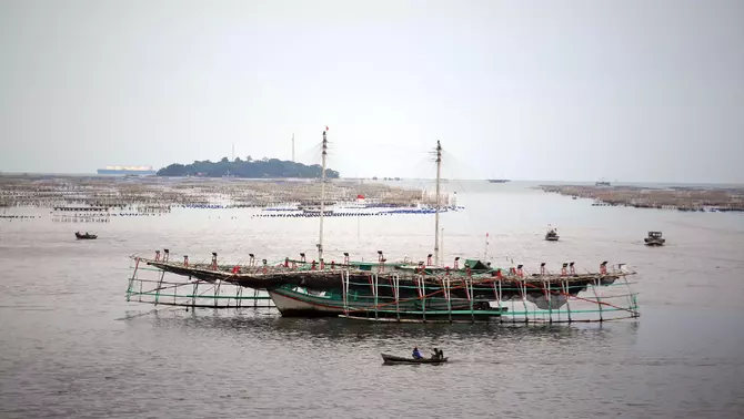 Nelayan menggunakan perahu melintas di dekat karamba jaring apung kerang hijau di laut Dadap, Tangerang, Banten, Selasa, 7 Februari 2023.