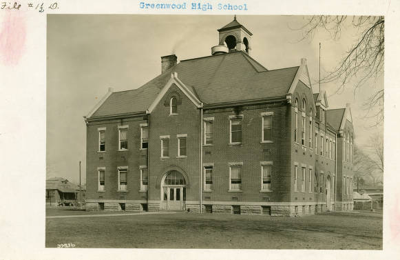 The Federal style, brick building has a steep roof with multiple gables and a cupola.