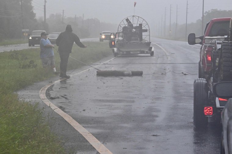 People move debris off a highway in Cross City, Florida, on August 30, 2023, after Hurricane Idalia made landfall. Idalia barreled into the northwest Florida coast as a powerful Category 3 hurricane on Wednesday morning, the US National Hurricane Center said. "Extremely dangerous Category 3 Hurricane #Idalia makes landfall in the Florida Big Bend," it posted on X, formerly known as Twitter, adding that Idalia was causing "catastrophic storm surge and damaging winds." (Photo by Chandan Khanna / AFP) (Photo by CHANDAN KHANNA/AFP via Getty Images)