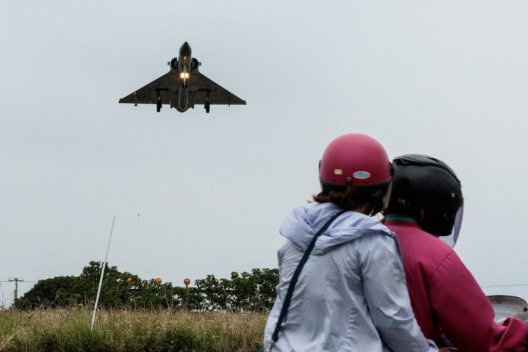 TOPSHOT - -- AFP PICTURES OF THE YEAR 2024 -- Two people ride a motorcycle as a Taiwanese Air Force Mirage 2000 fighter jet approaches for landing at an air force base in Hsinchu after China encircled Taiwan with naval vessels and military aircraft in war games exercises, in northern Taiwan on May 23, 2024.?? (Photo by Yasuyoshi CHIBA / AFP) / AFP PICTURES OF THE YEAR 2024 (Photo by YASUYOSHI CHIBA/AFP via Getty Images)