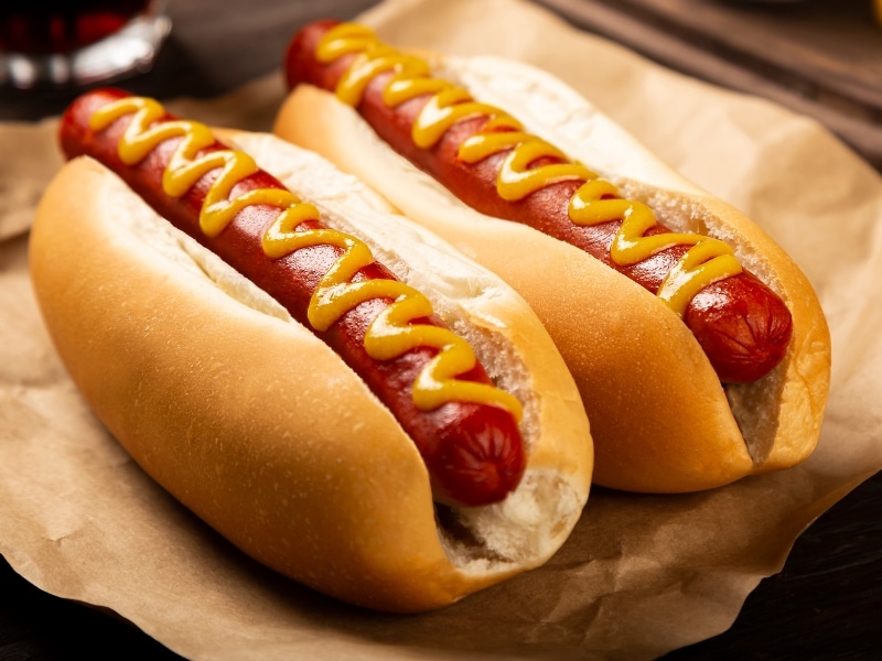 Hot Dogs on a Parchment Paper with Mustard on Top