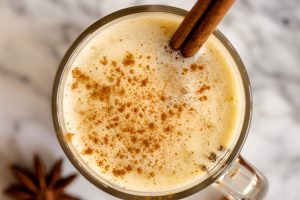 Super Close Top View of Hot Buttered Rum in a Glass with a Dusting of Cinnamon, Garnished with a Cinnamon Stick