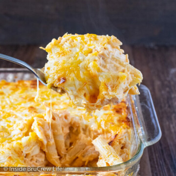 A casserole dish of buffalo chicken pasta with a spoon lifting pasta out.