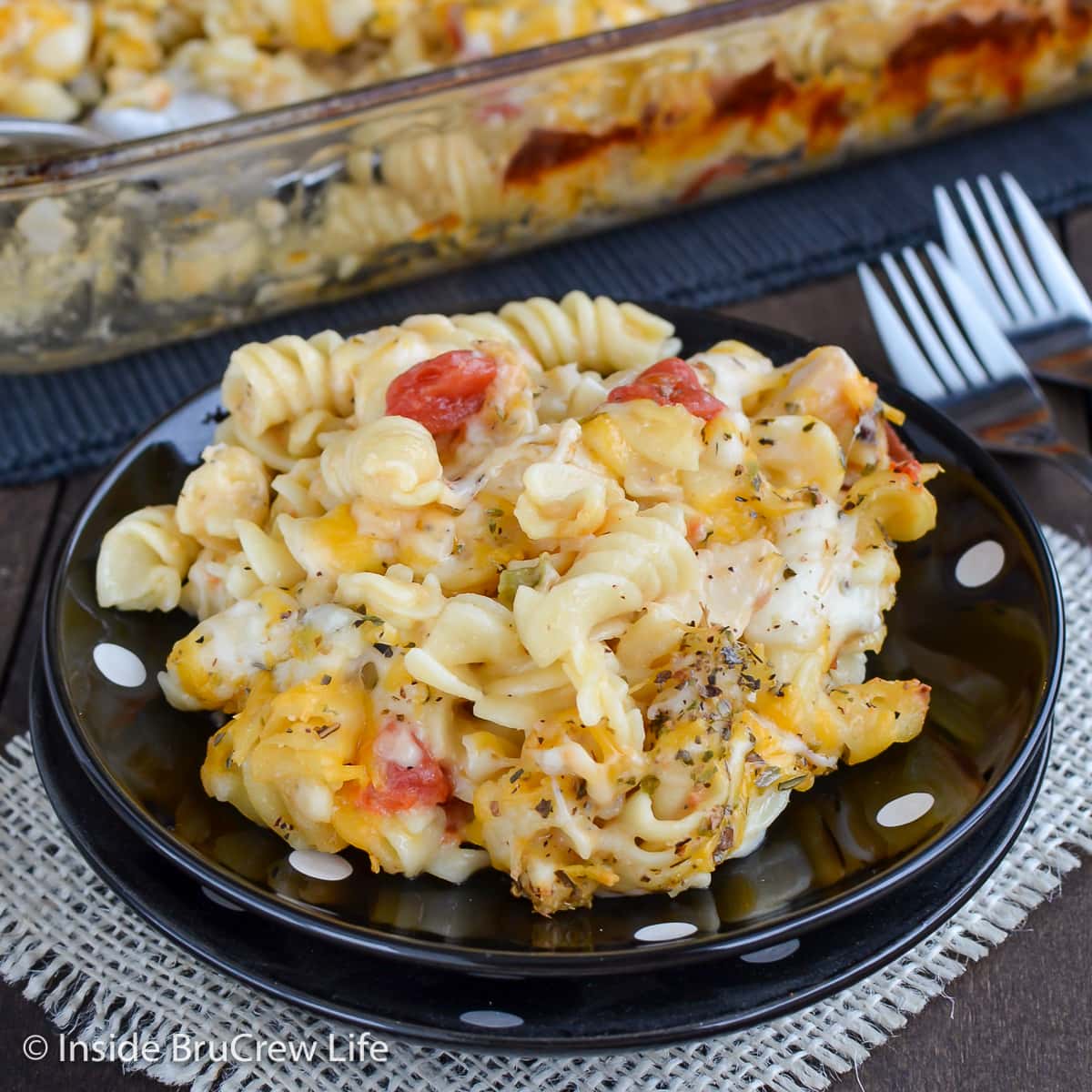 A black plate with a serving of baked pasta on it.