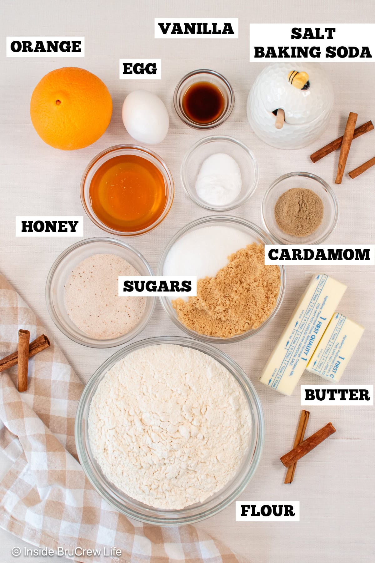 A white board with bowls of ingredients needed to make orange sugar cookies.