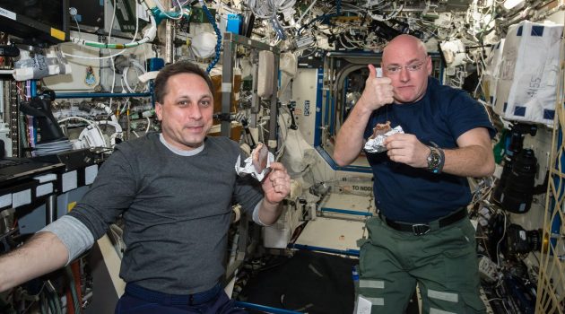 NASA astronaut Scott Kelly gives the "high sign" on the quality of his snack while taking a break from his work schedule aboard the International Space Station on Apr. 20, 2015. Russian cosmonaut Anton Shkaplerov (ROSCOSMOS) seems to agree on the tasty factor of the specially prepared space food. (Photo courtesy NASA)