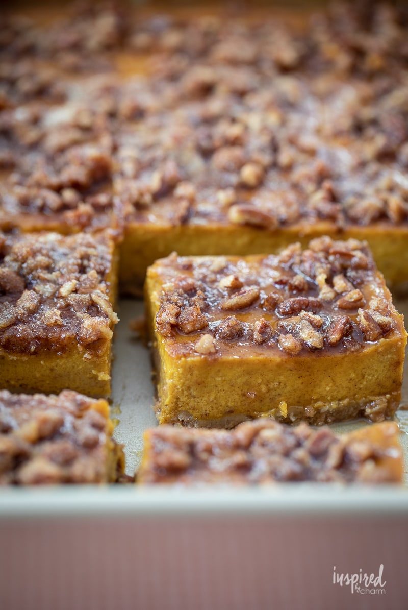 close up of a piece of pumpkin pie bar in the pan with more. 