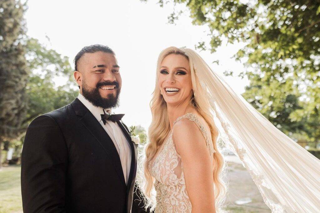 Charlotte Flair is standing with her husband in wedding outfits and posing for the picture