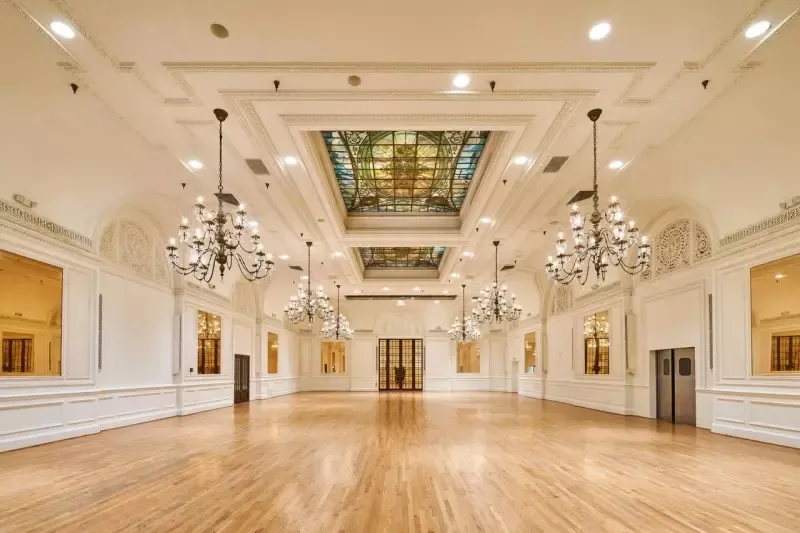 A large empty room with hardwood floors and a stained glass ceiling.