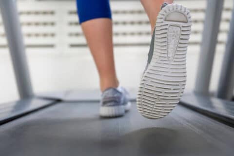 A woman running on a treadmill wearing trail shoes