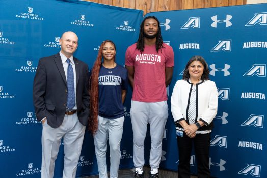 Two males, two females standing and smiling