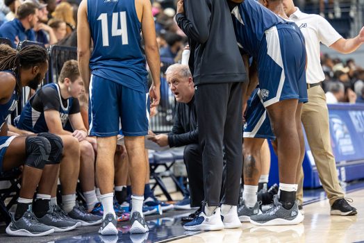 Man kneeling talking to basketball players